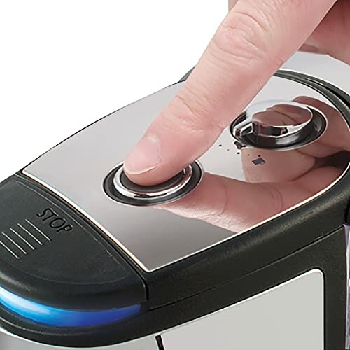 Finger pressing button on coffee maker control panel.